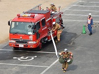 写真:現場到着し、隊員が消火用ホースを延長している様子